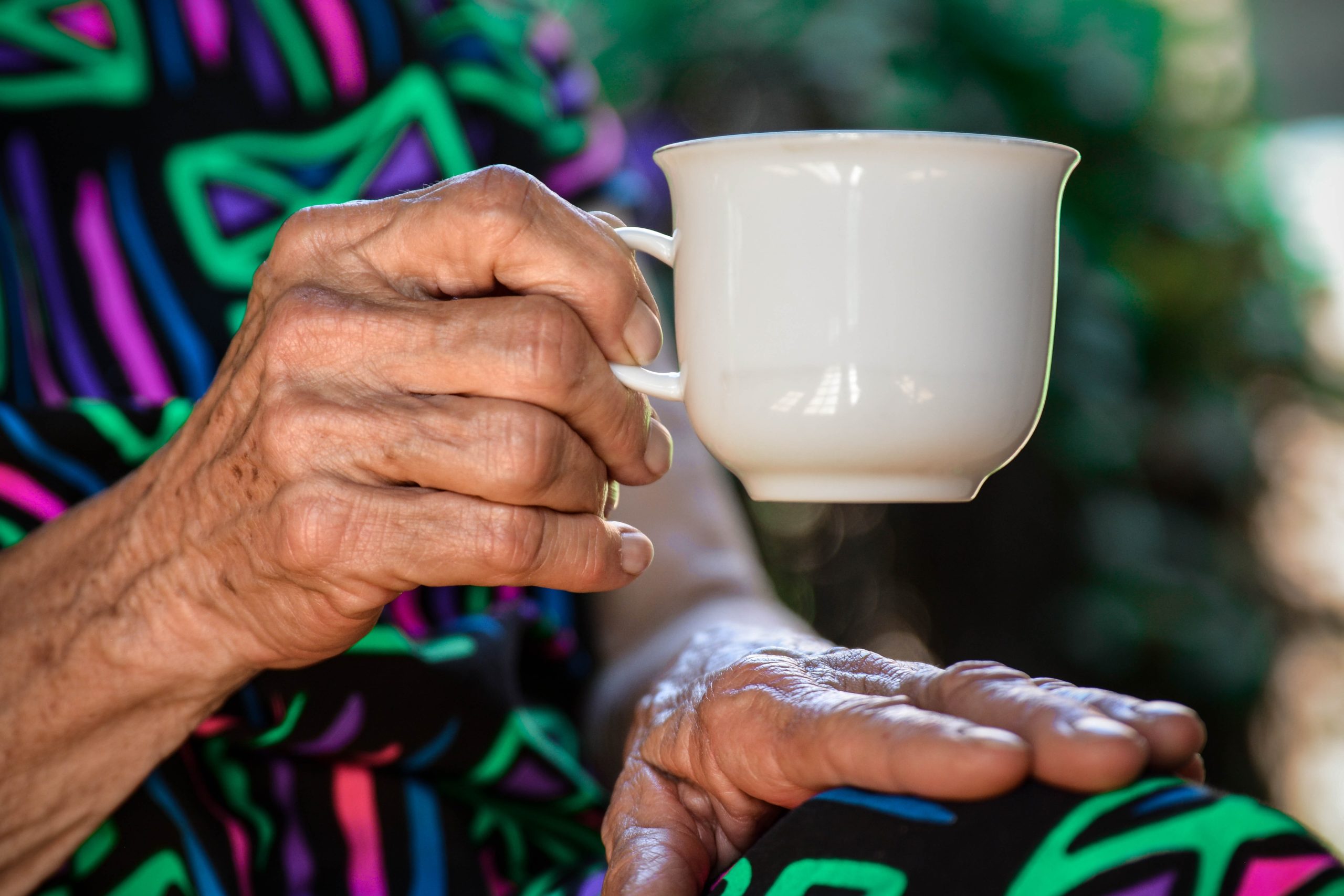 Elderly woman holding a cup.